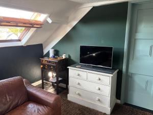 ein Wohnzimmer mit einer Couch und einem Fernseher auf einer Kommode in der Unterkunft Bear House B&B, Ensuite room above the Brachio Cafe, Colyton in Colyton
