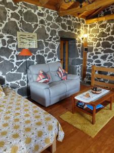 a living room with a couch and a stone wall at Casa do Bernardo in Feiteira