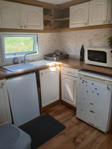 a kitchen with white cabinets and a sink and a microwave at Mobile home in Liscannor