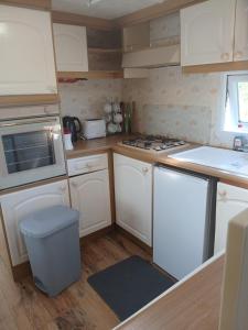 a kitchen with white cabinets and a stove top oven at Mobile home in Liscannor