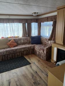 a living room with a couch in front of a window at Mobile home in Liscannor