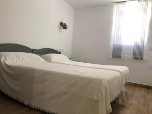 a white bed in a white room with a window at Entre Micelios in Vinuesa