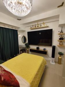 a bedroom with a yellow bed and a flat screen tv at CA Smart Staycation at Azure North in Lagundi