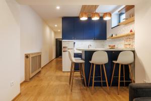 a kitchen with blue cabinets and white stools at ARIETES MARMONT Apartmány in Tatranska Strba