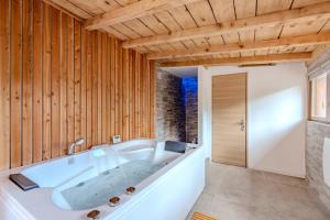 a large white tub in a bathroom with wooden walls at PINOT GRIS - Charmant studio au cœur du vignoble - parking gratuit in Riquewihr +26 photos