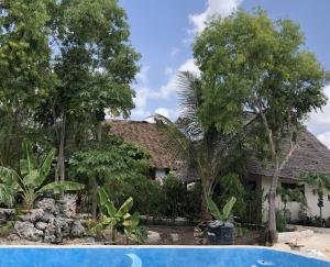 a house with a swimming pool and trees at Nanakizilodge in Mtendeni