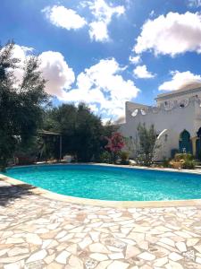 a swimming pool in front of a building at Dar Mimouna Djerba in Tianest