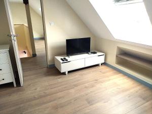 a living room with a tv on a white cabinet at Ker Louwen chambre d' hôte in Corseul