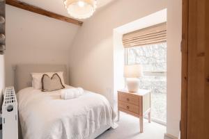 a white bedroom with a bed and a window at Critchlow Cottage in Buxton