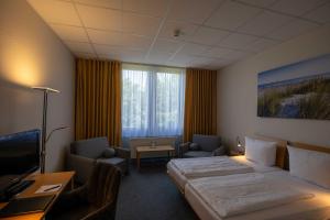 a hotel room with a bed and chairs and a television at DLRG Tagungszentrum Hotel Delphin in Bad Nenndorf +30 photos
