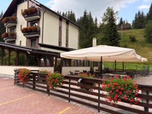 a restaurant with an umbrella and flowers in front of a building at PENSIUNEA SKY HUB in Arieşeni +14 photos