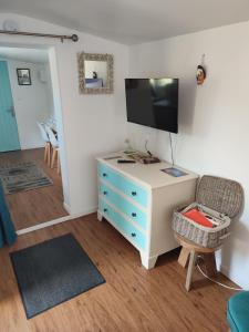 a room with a dresser with a tv and a chair at Gîte insolite La Renouée in Saumur