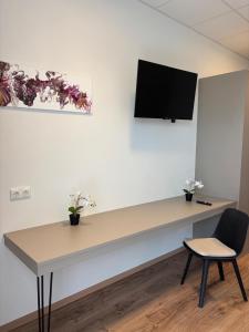 a desk with a tv on a wall with a chair at Motel Smart in Bogen