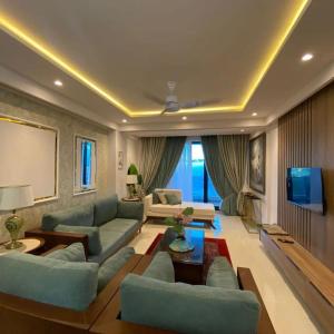 a living room with blue couches and a tv at Park Ridge Hotel Serviced Apartments - One Bedroom Apartment in Murree