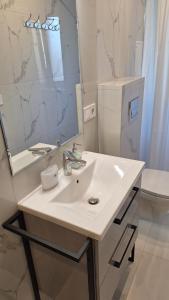 a white bathroom with a sink and a mirror at Petite Haven in Grobiņa
