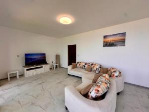 a living room with two couches and a flat screen tv at Бунгала " SEA VILLAGE DAR " in Kamchia