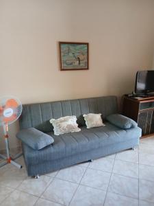 a blue couch in a living room with a tv at Nikoletta in Ancient Epidauros