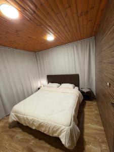 a bedroom with a large bed with a wooden ceiling at Cozy farm in Jerash