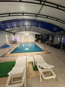 a pool with two lounge chairs and a swimming pool at Cozy farm in Jerash