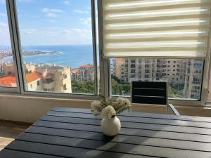 Eine weiße Vase mit Blumen auf einem Tisch vor einem Fenster in der Unterkunft Steph in Al Bāţiyah
