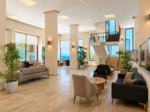 a lobby with couches and chairs and a staircase at Altamare Hotel in Kuşadası