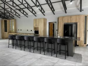 a kitchen with a large black counter with bar stools at Fairview Guest House Executive in Hartswater