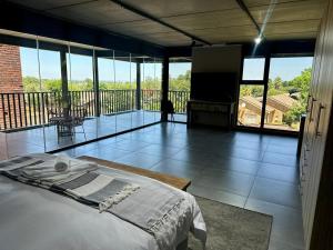 a bedroom with a bed and a balcony with windows at Fairview Guest House Executive in Hartswater