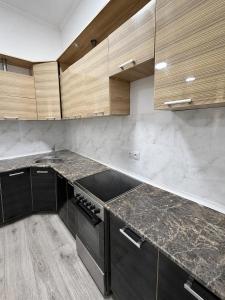 a kitchen with marble counter tops and wooden cabinets at Global Hostel 3 in Almaty