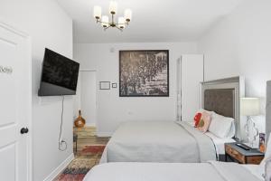 a white bedroom with two beds and a tv at Serenity Inn in Niagara Falls