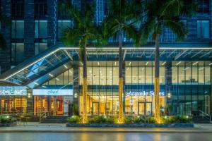 a large building with palm trees in front of it at H-Vista WestGate Suites in Hanoi