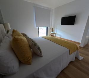 a bedroom with a large white bed with yellow pillows at RR Pico in São Mateus