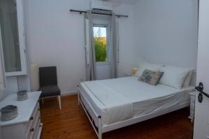 a bedroom with a bed and a window and a chair at Casa Sulla Montagna North Corfu in Loútsai