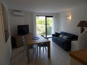 Una sala de estar con una mesa y un sofá azul. en Villa 8 au Village Marin, en Porto Vecchio