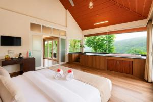 a bedroom with a large bed and a large window at Silent Brook Resort - Coorg in Madikeri