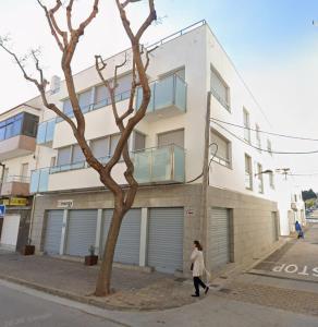 a woman walking down a street in front of a building at Urpa Apartaments in Llança