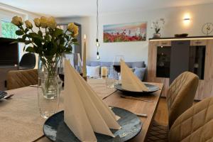 a dining room table with plates and flowers on it at Relax Apartment Lakewalk in Friedrichshafen