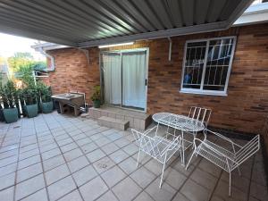 a patio with a table and chairs and a brick wall at Glendale Cottage in Bloemfontein