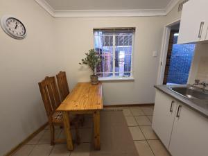 a kitchen with a wooden table and chairs and a clock at Glendale Cottage in Bloemfontein
