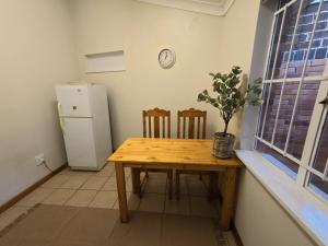 a kitchen with a wooden table and a refrigerator at Glendale Cottage in Bloemfontein