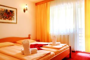 2 Betten in einem Hotelzimmer mit Handtüchern darauf in der Unterkunft Pensiunea Mai in Răşinari