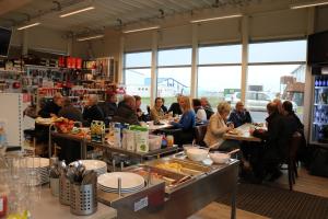Eine Gruppe von Menschen sitzt an Tischen in einem Restaurant in der Unterkunft Thorshamar sea side villa in Þórshöfn