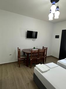 a living room with a table and chairs and a tv at Arval Rooms in Vlorë