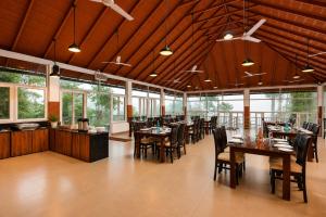 a restaurant with wooden ceilings and tables and chairs at Silent Brook Resort - Coorg in Madikeri