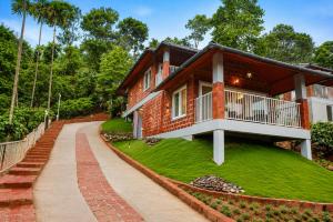 a brick house with a balcony on a grassy hill at Silent Brook Resort - Coorg in Madikeri