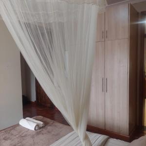 a bedroom with a bed with a white curtain at HARMONY GUEST house in Nairobi