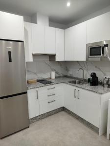 a kitchen with white cabinets and a stainless steel refrigerator at Aires de Chipiona Apartamento B in Chipiona