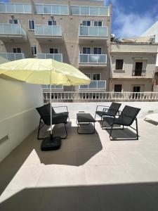 a patio with chairs and an umbrella on a building at Maltese House Gzira Central in Il-Gżira