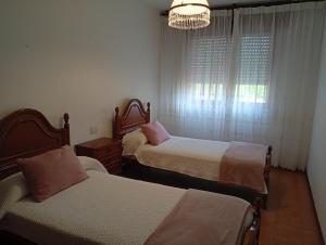 a bedroom with two beds and a window with a chandelier at Piso centro de Raxò in Raxó