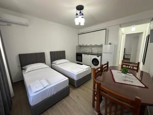 a room with two beds and a table and a dining room at Arval Rooms in Vlorë