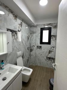 a bathroom with a white toilet and a sink at Arval Rooms in Vlorë +20 photos